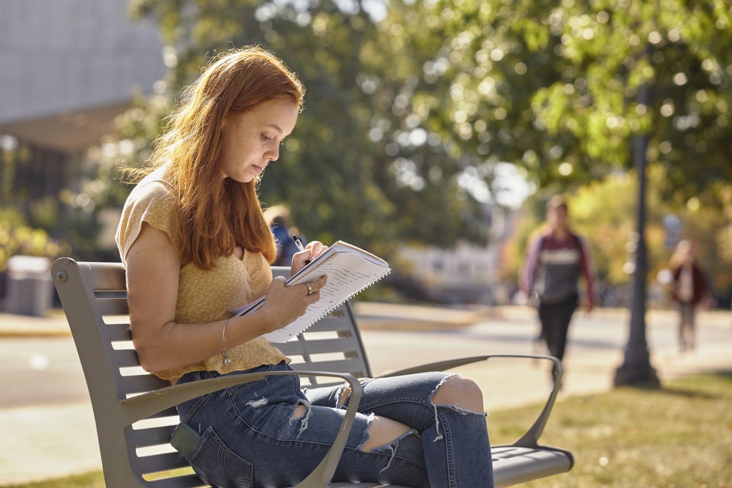 一位<a href='http://omc.961381.com'>bv伟德ios下载</a>学院的学生在校园里的长椅上读书.